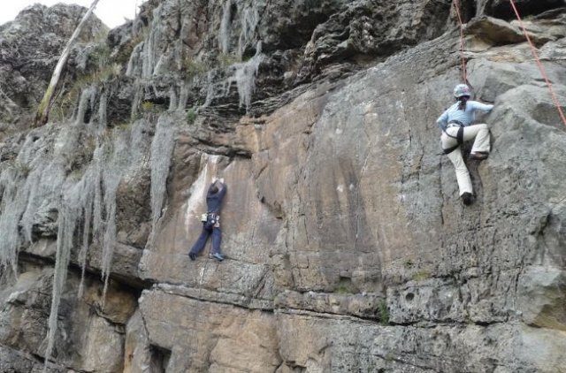dos hombres escalando por una pared